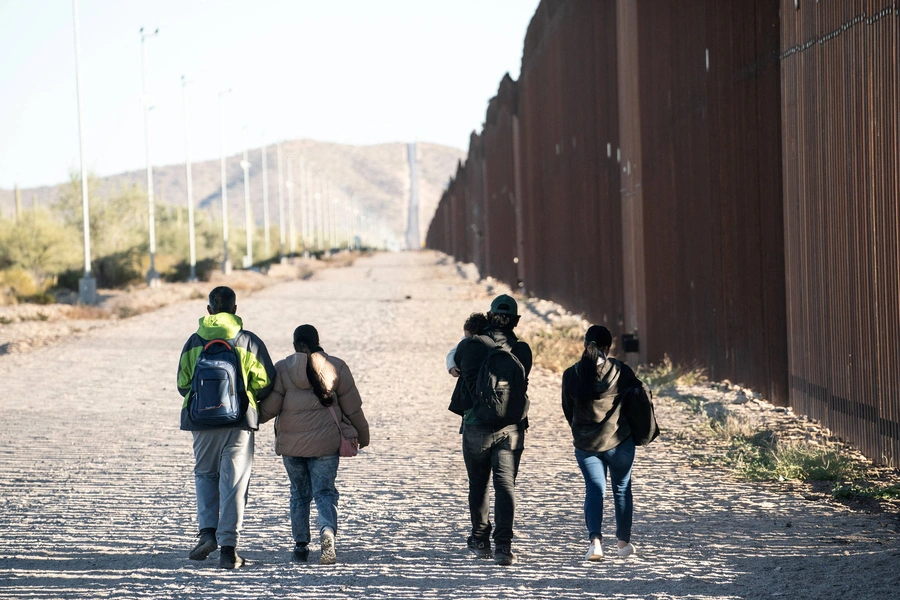 Migrants walk toward a staging area to be transported by the U.S. border patrol after crossing the U.S. border in Lukeville, Arizona, on December 13, 2023.